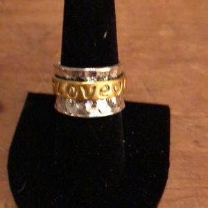 silver spinner ring has the word love engraved 3 times around the gold band.